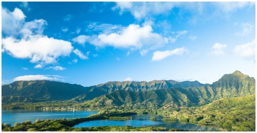 Scenic view of lush mountains and a lake under a b