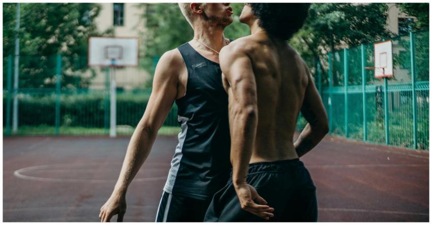 Two men playing basketball outdoors with focus on