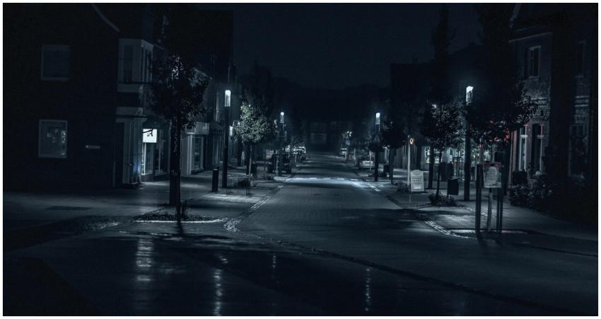 A quiet and dimly lit urban street scene at night,