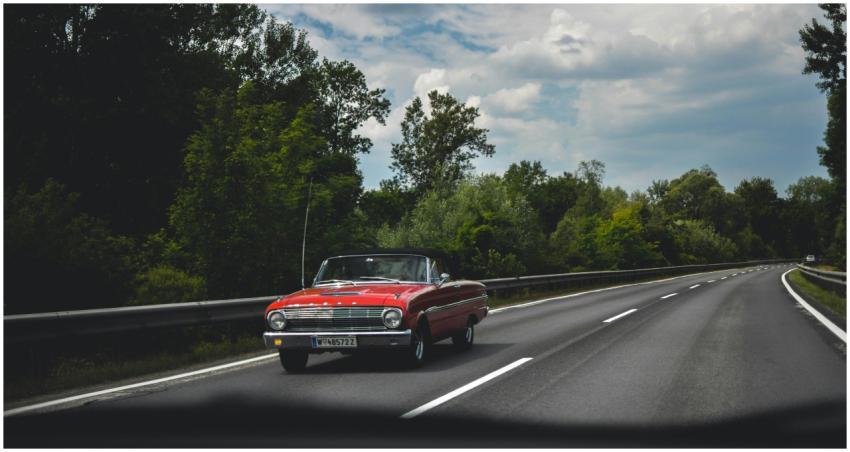 Vintage red convertible cruising along a scenic hi