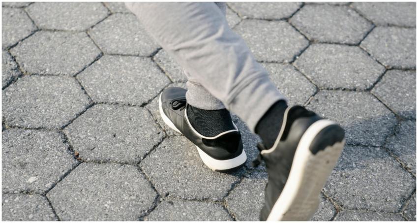 Jogger's feet in black sneakers moving on a paved