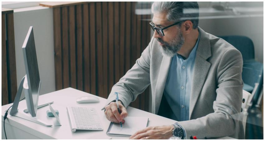 A mature businessman taking notes at his desk with