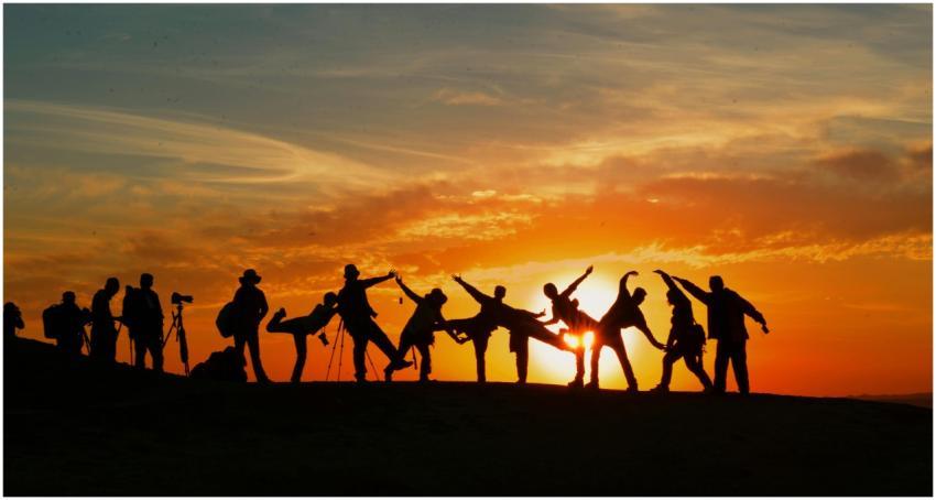Group of people silhouetted against a vibrant suns