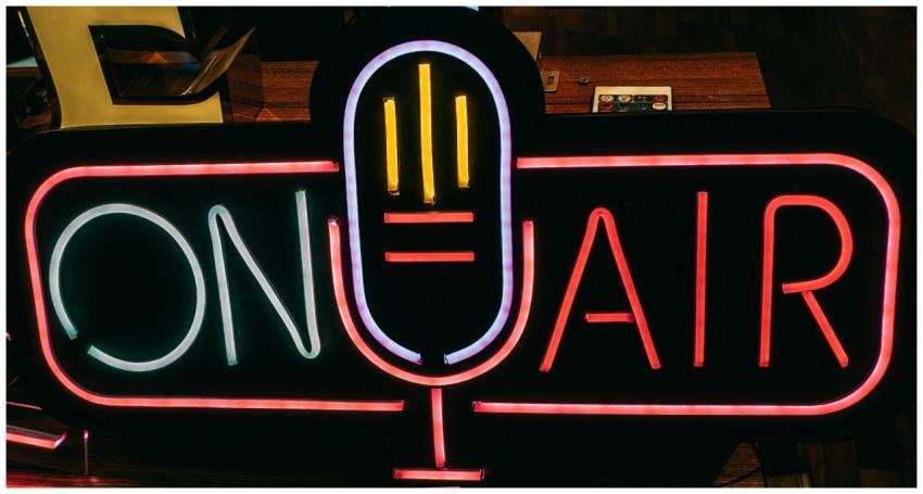 Bright neon 'On Air' sign glowing in a dark studio