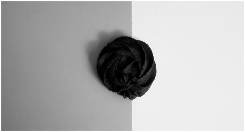 An artistic black meringue displayed on a contrast