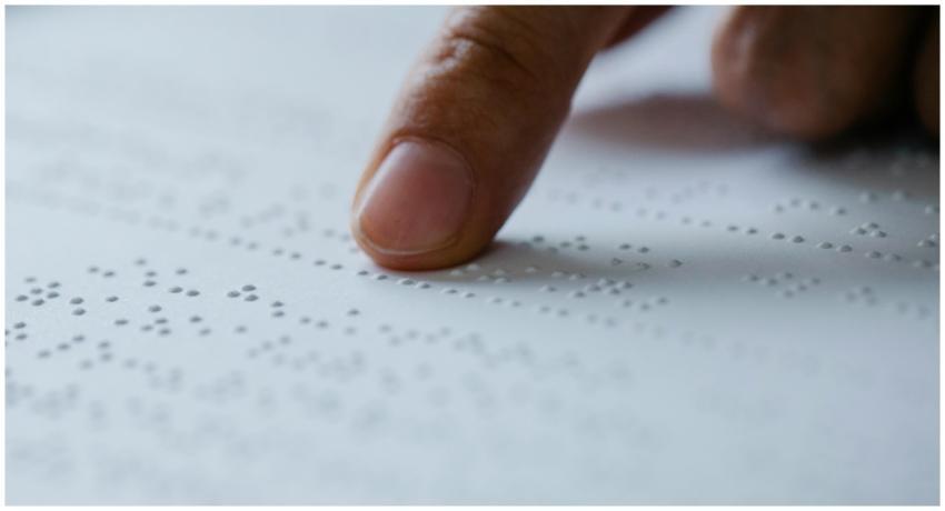Close-up of a finger reading braille text on a tex