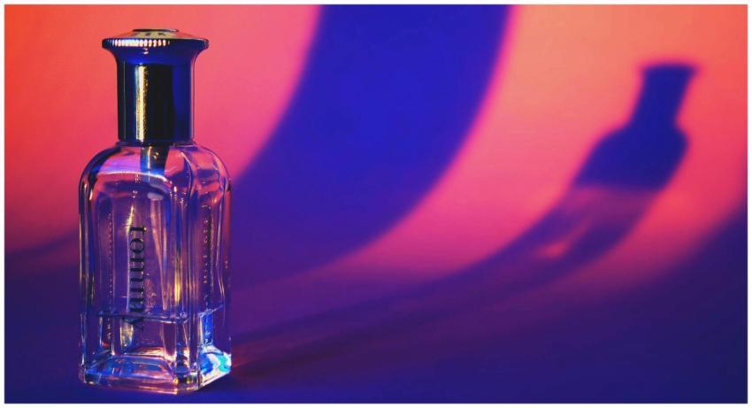 A glass perfume bottle casting vibrant shadows in
