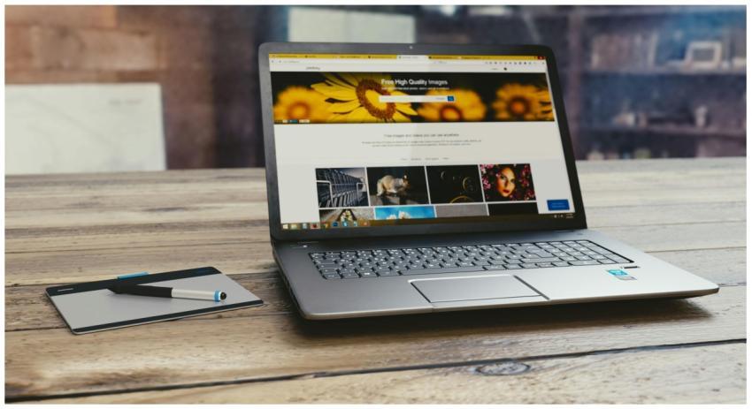 Laptop with open webpage on wooden desk, accompani