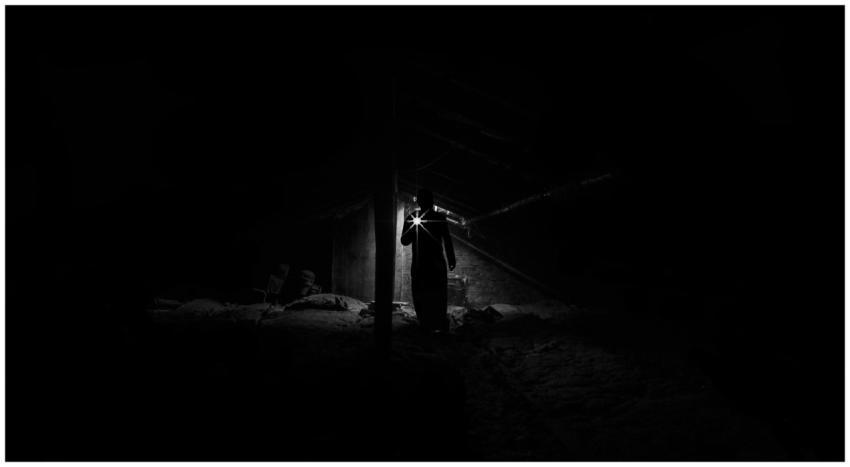 A shadowy figure explores a dimly lit, eerie attic