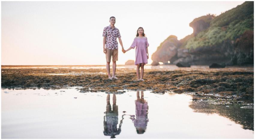 A young couple holding hands on a beach with their