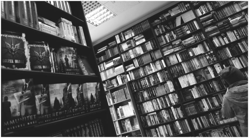Black and white image of a person browsing bookshe