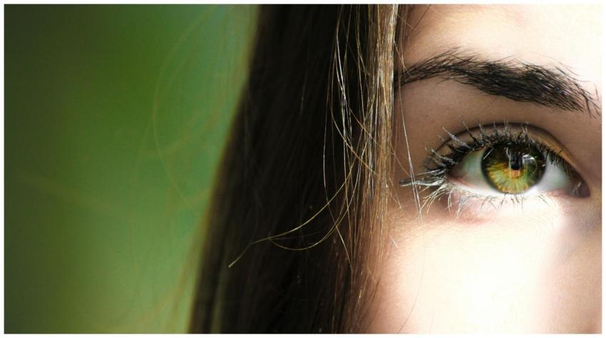 A detailed close-up of a woman's eye with green ir