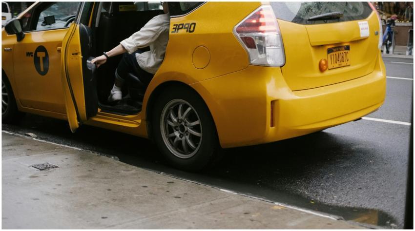 Unrecognizable passenger closing door of yellow ca