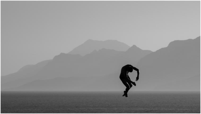 Silhouette of a man diving over the sea with mount