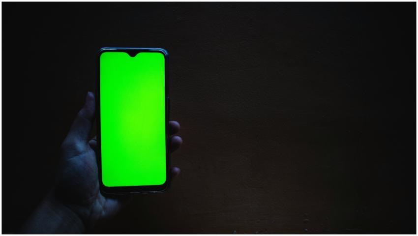 Smartphone with a vivid green screen held against