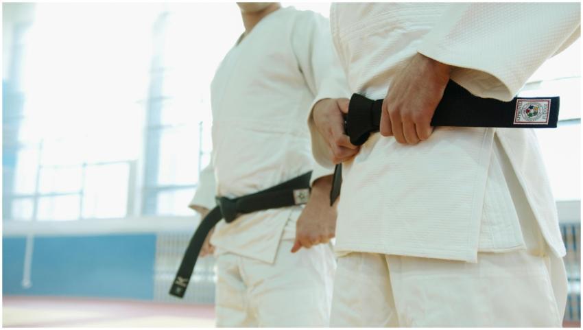 Two martial artists in white uniforms holding blac