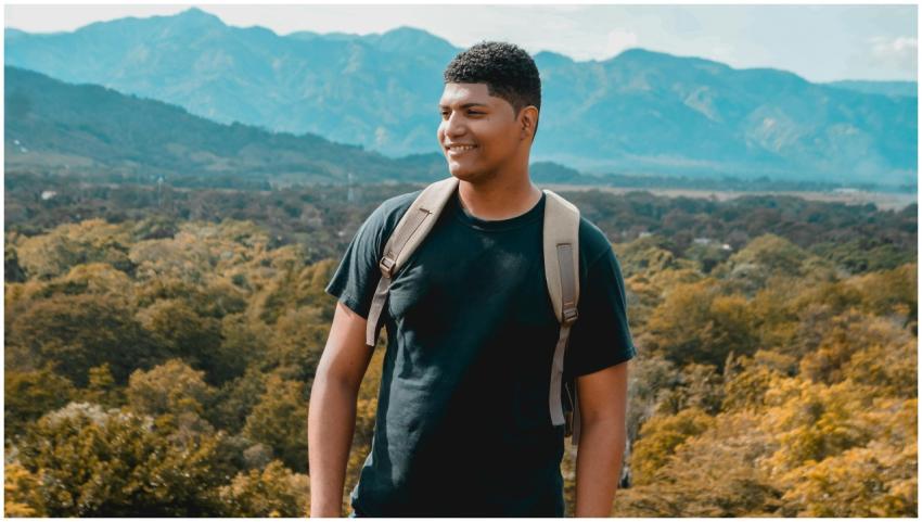 A smiling young backpacker enjoys a scenic view in