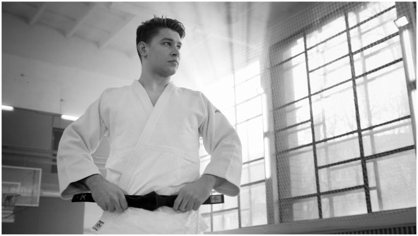 A young martial artist adjusts his black belt in a