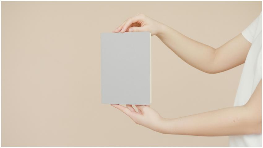Hands holding a blank book cover for creative desi