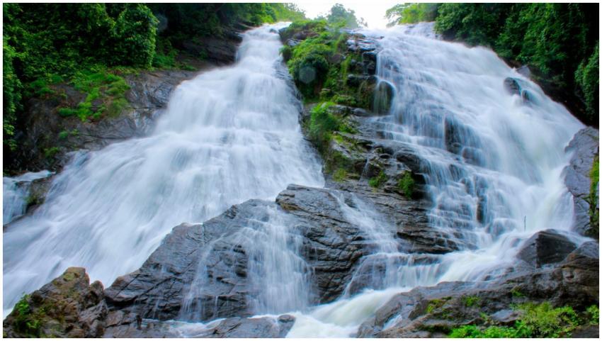 A stunning waterfall flows through vibrant green f