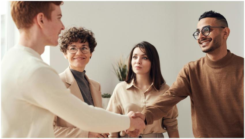 Four colleagues in an office handshake demonstrati