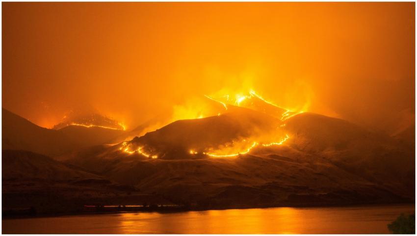 Intense wildfire blazing on hills, reflecting over