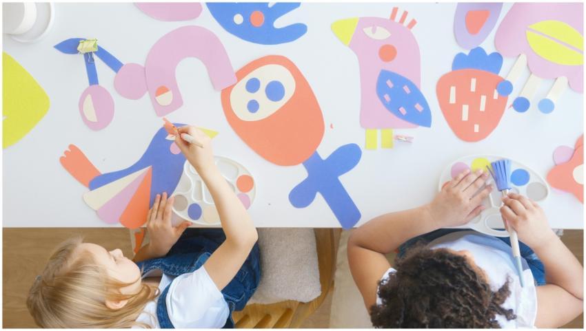 Two children at a table working on colorful paper