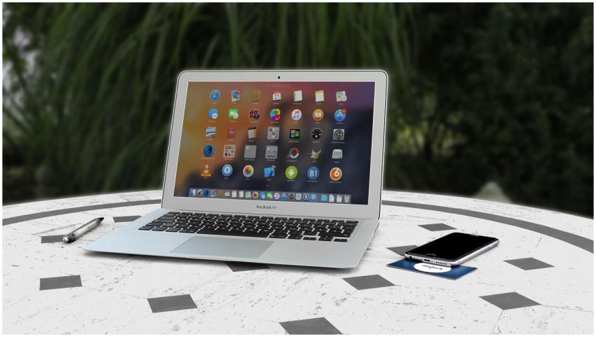 Open laptop with app icons displayed, smartphone a