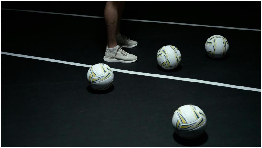 Person in sneakers with volleyballs on indoor cour