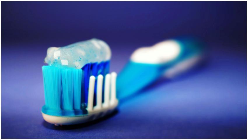 Macro shot of a toothbrush with blue toothpaste an