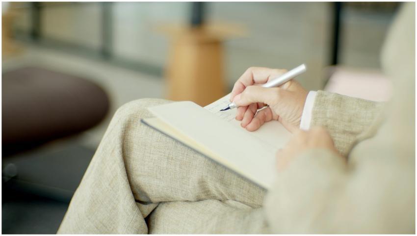 Close-up of a person writing in a notebook with a