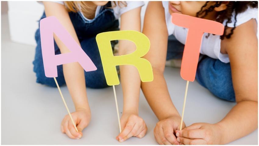 Children playing with colorful paper cutouts spell