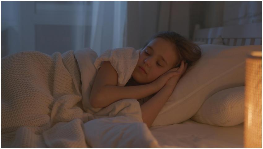 A serene child sleeping in a warmly lit cozy bedro