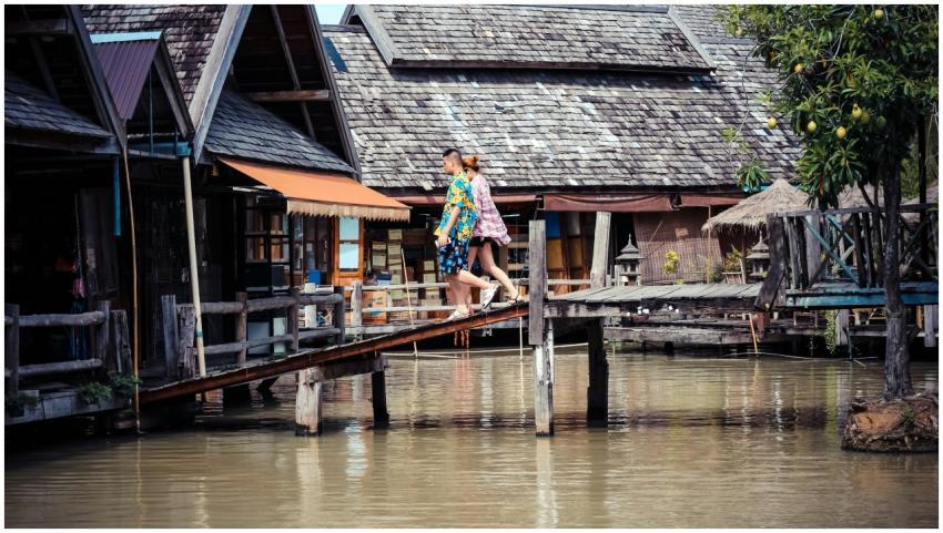 A couple walks across a wooden bridge in a traditi