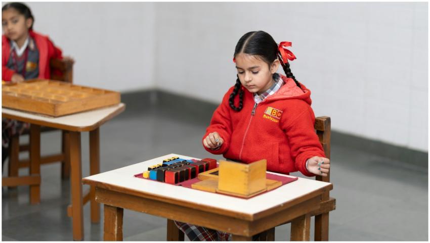 A young girl in a classroom focused on a Montessor