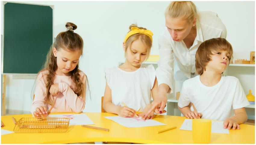 A teacher helping young children with drawing acti