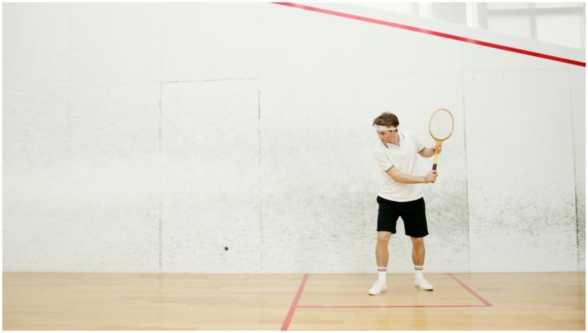 A male squash player in action, ready to strike a