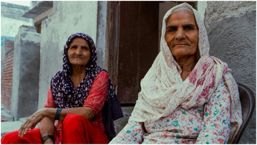 Two elderly women wearing traditional clothing rel