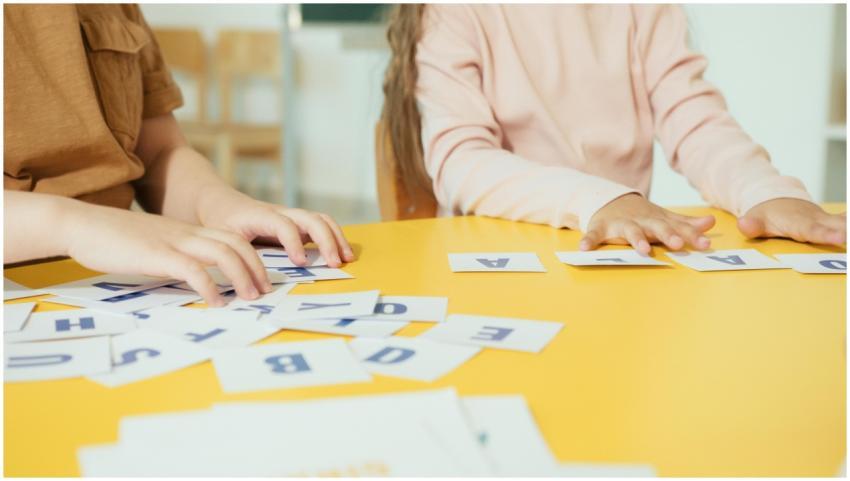 Children arranging alphabet cards on a yellow tabl
