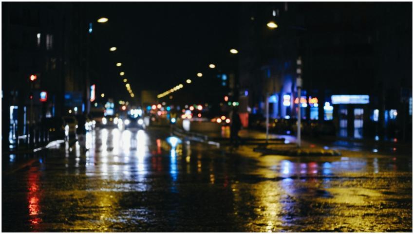 Blurred urban street at night with reflections of
