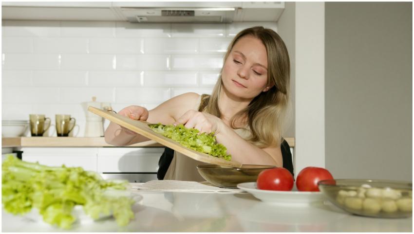 A woman preparing a fresh salad with lettuce and t