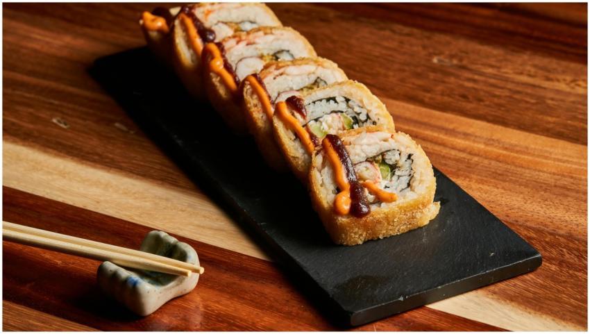 Gourmet sushi roll with spicy sauce on slate with