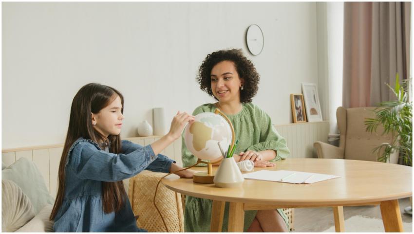 A child studies a globe with a teacher, engaging i