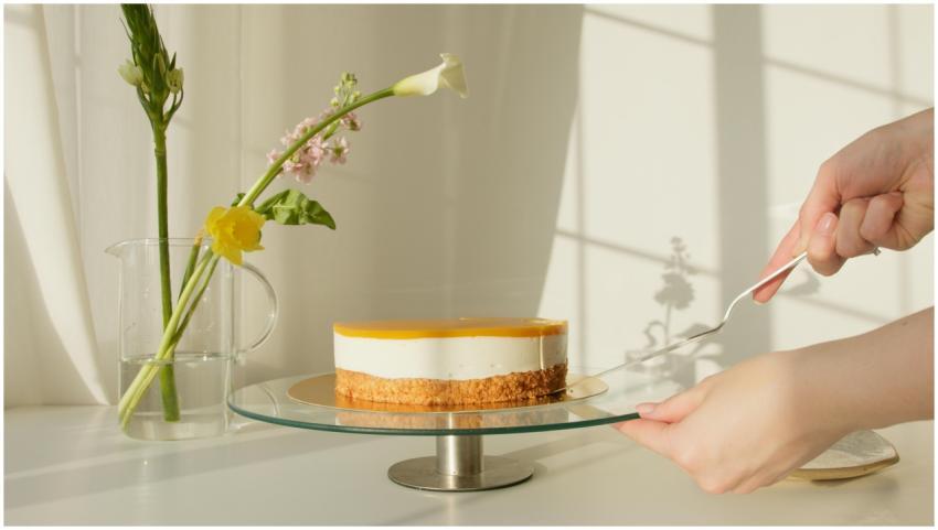 Elegant lemon cheesecake on a stand surrounded by