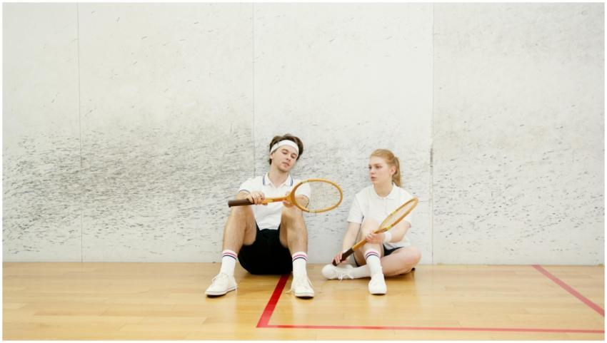 Two young squash players resting on an indoor cour