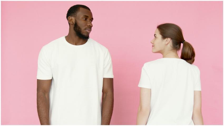 A man and woman in white t-shirts stand against a