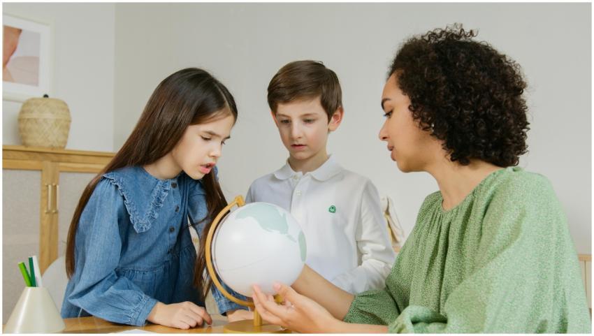 A teacher and two children exploring a globe indoo