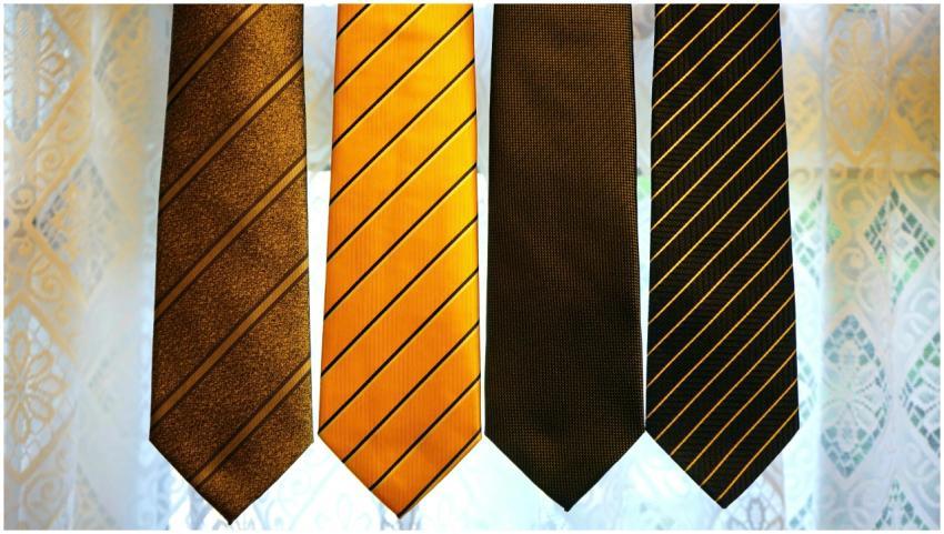 Four elegant striped ties hanging against a patter