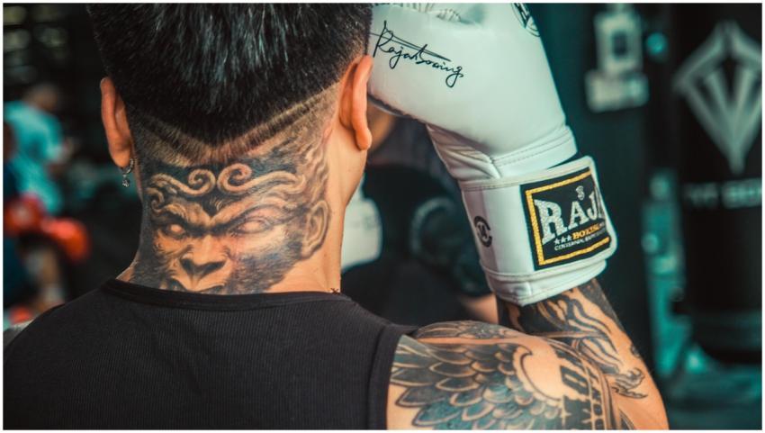A boxer with intricate tattoos and boxing gloves g