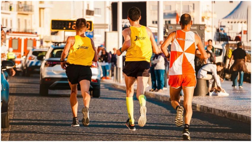 Three athletes running in a city marathon on a sun
